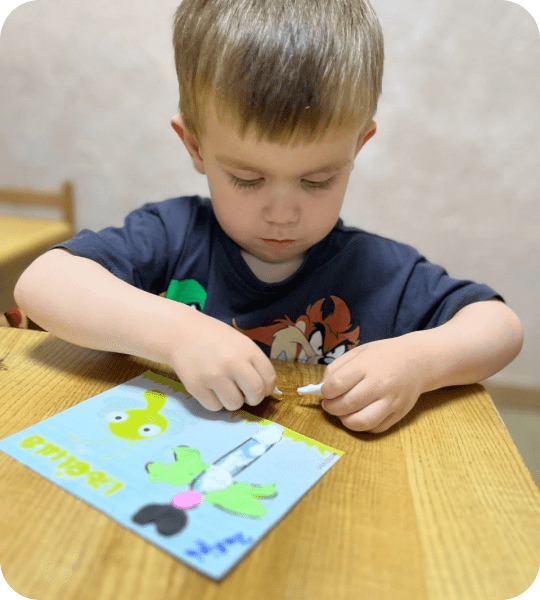 Хлопчик робить аплікацію пластиліном